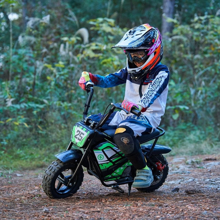 A child in protective gear and helmet rides a MotoTec 24v 250w Electric Mini Bike Black by MotoTec on a rugged forest trail.