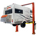 A motorhome is elevated on an AMGO Hydraulics OH-12 12,000 lbs 2 Post Lift, revealing its underside and rear.