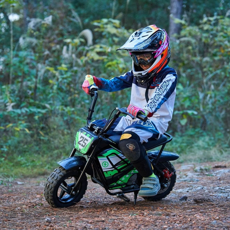 A child in protective gear and helmet rides a MotoTec 24v 250w Electric Mini Bike Black by MotoTec on a rugged forest trail.