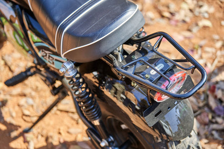 Close-up of the rear section of a MotoTec 60v 1500w Electric Powered Mini Bike Lithium Black, showcasing the seat, rear rack, suspension, and taillight on a dirt ground.