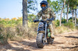 A person in camouflage gear and helmet rides a rugged dirt bike, like the MotoTec 60v 1500w Electric Powered Mini Bike Lithium Black, along a forest trail.