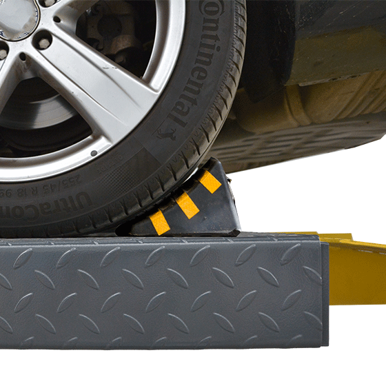 Rubber wheel chock placed against a vehicle tire on the lift runway