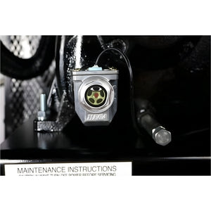 Chrome oil-level sight glass with low-oil shut-off sensor and wiring, mounted above the maintenance-instructions label
