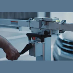 MA600 frame target-arm extension close-up showing the central pivot housing and a technician's hand on the adjustment handle