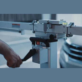 Technician using hand crank on MA600 frame column to adjust height with vehicle in background