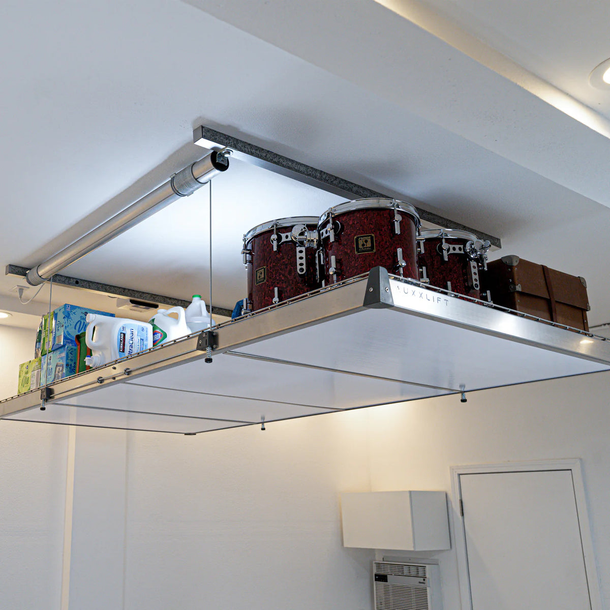 Auxx-Lift ceiling storage platform loaded with boxes and gear, semi-transparent cover on the underside