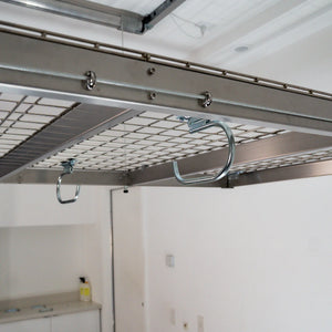 Two zinc-finished hooks installed on the underside wire deck of an overhead garage storage rack