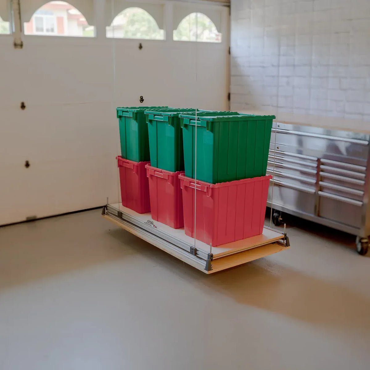 Attic-Lift platform on the garage floor loaded with six stacked storage totes