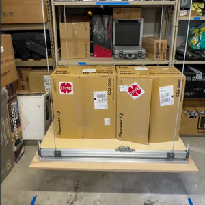 Attic-Lift platform lowered and loaded with two heavy equipment boxes in a storage room