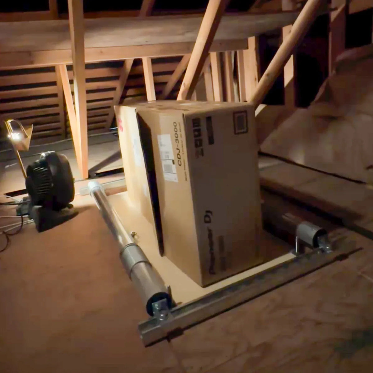 Attic-Lift delivering an equipment box up into an attic among the roof framing