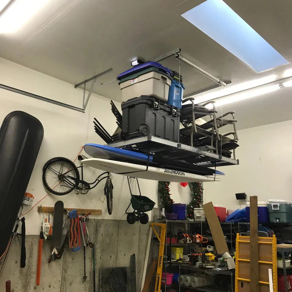 Heavily loaded Auxx-Lift platform with totes, folding chairs, and a paddleboard in a garage