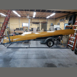 Auxx-Lift platform lowered to the floor holding a yellow kayak on a trailer in a workshop