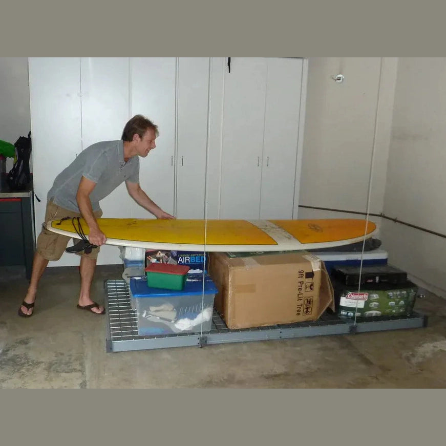 Man loading a surfboard and storage totes onto a waist-height Auxx-Lift platform