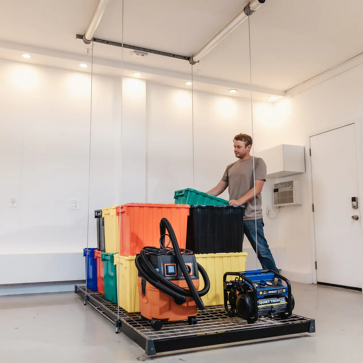 Man loading a tote onto a raised Auxx-Lift platform stacked with bins and tools