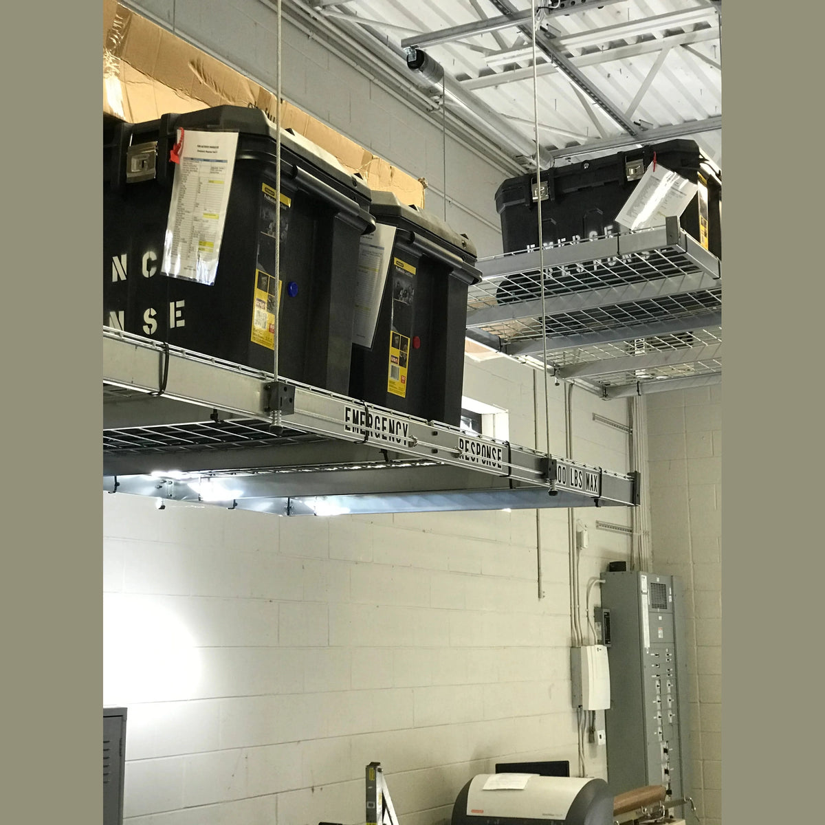 Auxx-Lift platform holding black Emergency Response totes in a cinder-block facility
