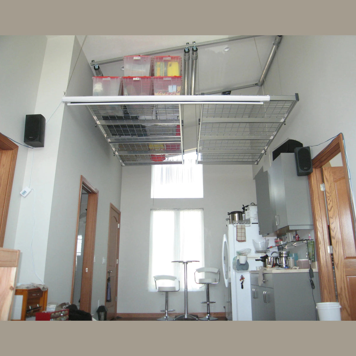 Auxx-Lift platform mounted high in a loft, holding clear storage totes with red lids