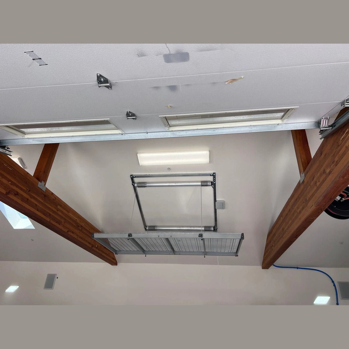 Auxx-Lift wire-mesh platform installed below a wood-beam garage ceiling