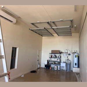 Empty Auxx-Lift platform mounted near the ceiling of a tall stucco garage