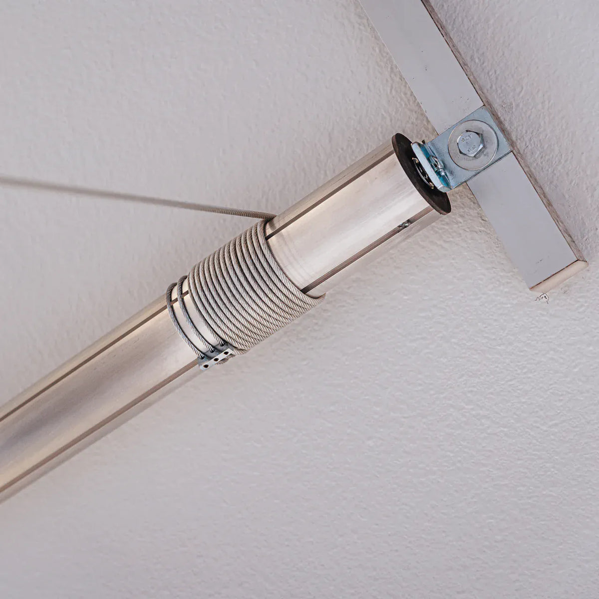 Steel lifting cable wound around an Auxx-Lift tubular motor bolted to the ceiling strut channel