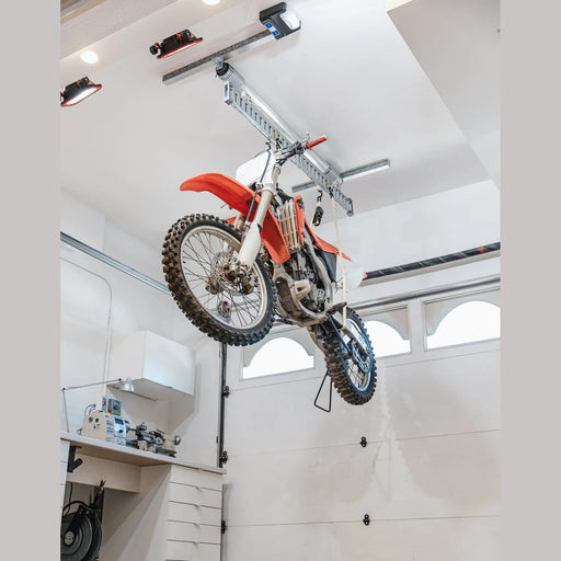 Orange dirt bike stored overhead in a garage on the Auxx-One ceiling lift