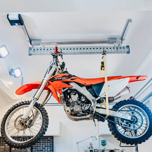 Orange dirt bike suspended from the Auxx-One ceiling lift E-Beam