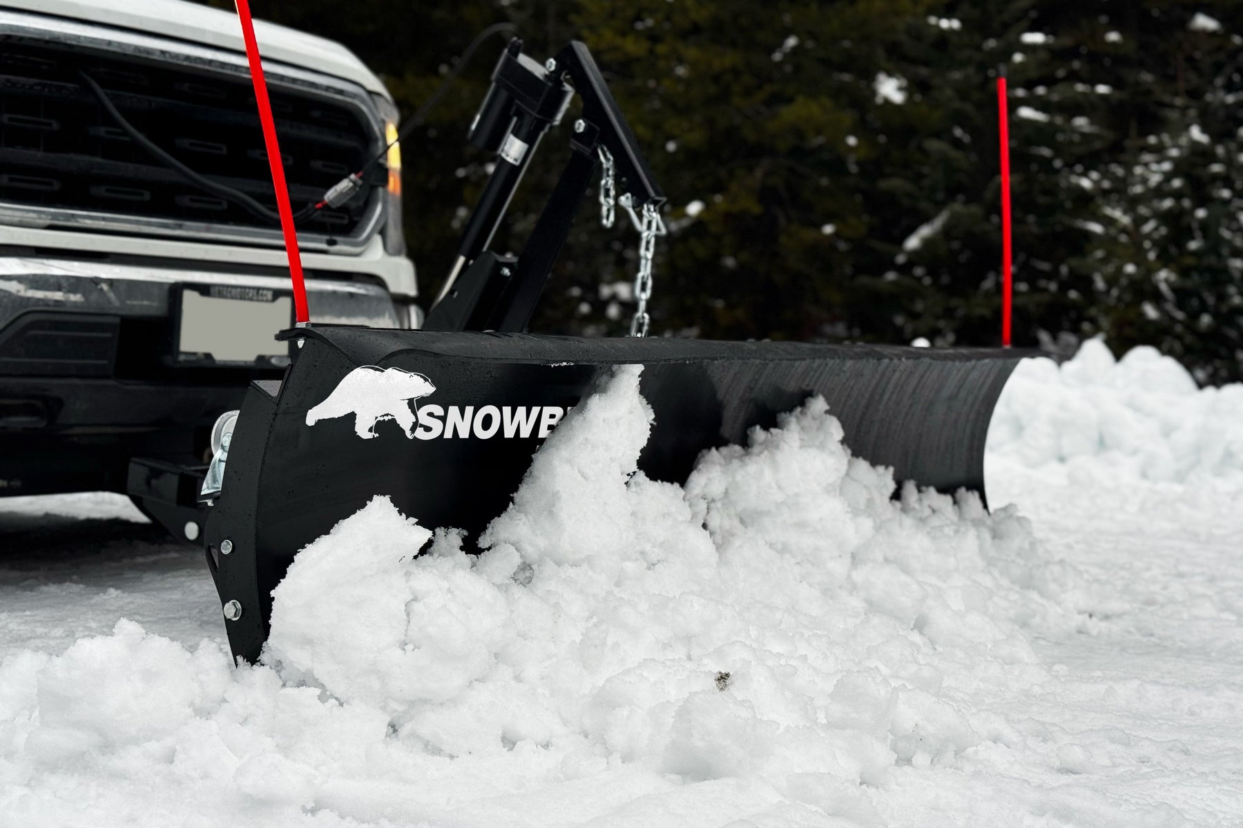 SnowBear Elite plow pushing snow with the actuator lift visible in front of a truck