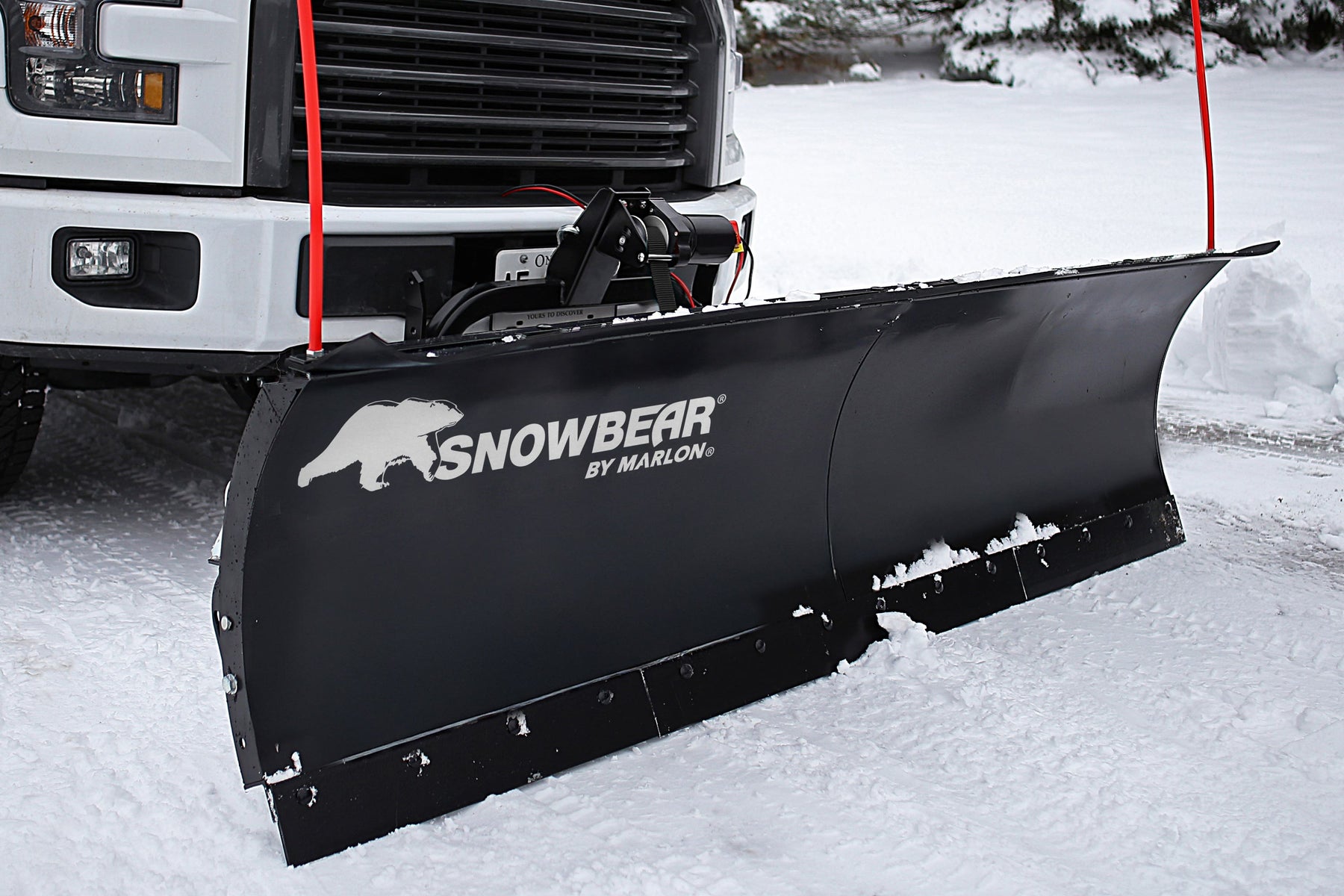 SnowBear snow plow mounted on a white pickup truck in snow