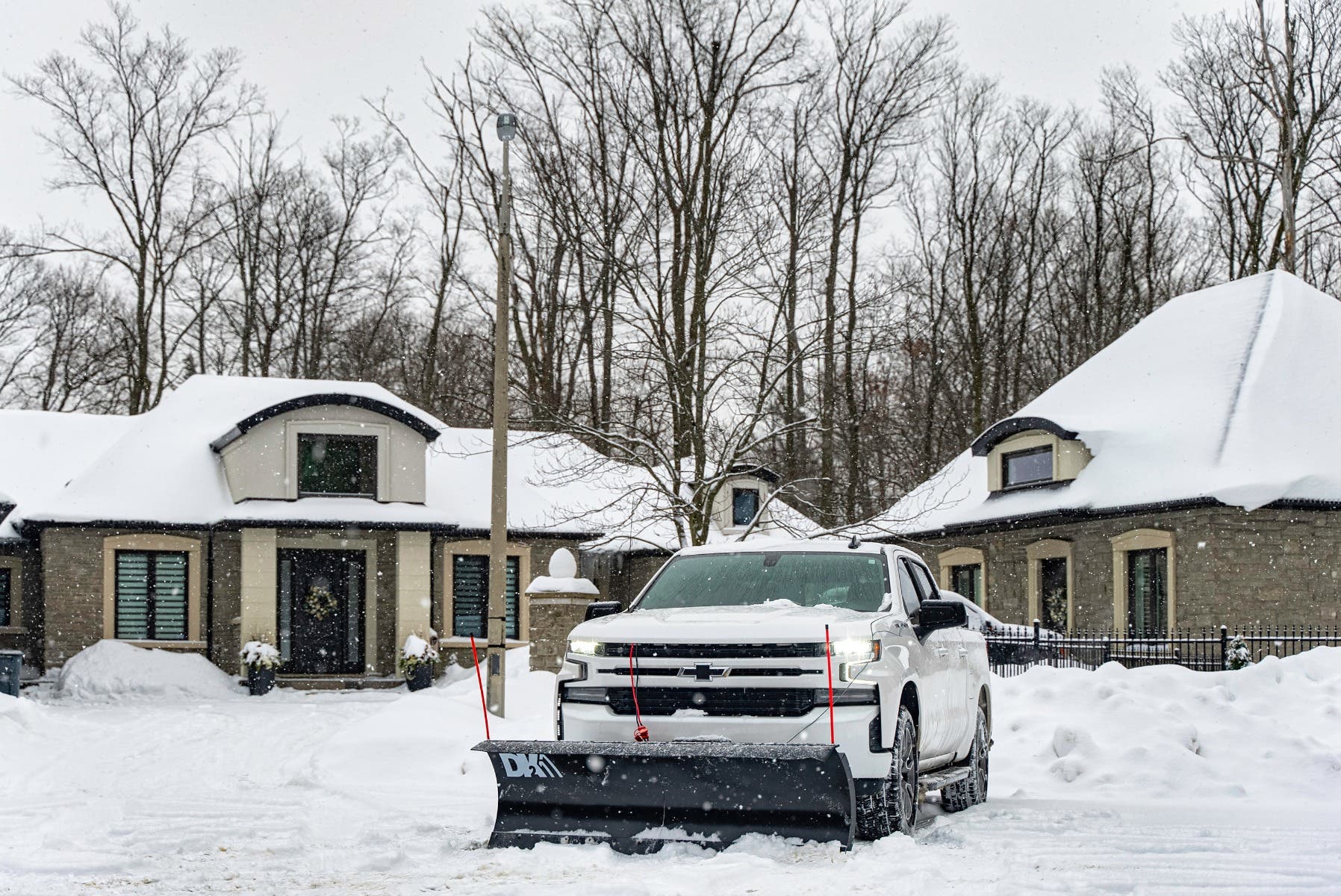 White pickup with the DK2 Everest plow on a snowy residential street