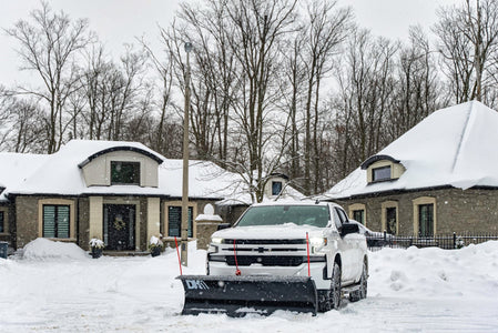 White pickup with the DK2 Everest plow on a snowy residential street
