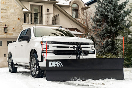 DK2 ELITE snow plow mounted on a white Chevrolet Silverado in a snowy driveway
