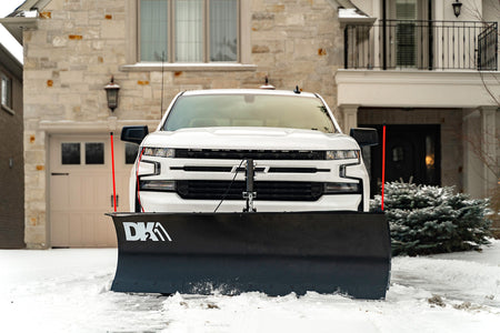 Front view of a white Chevrolet pickup with the DK2 ELITE snow plow lowered in snow