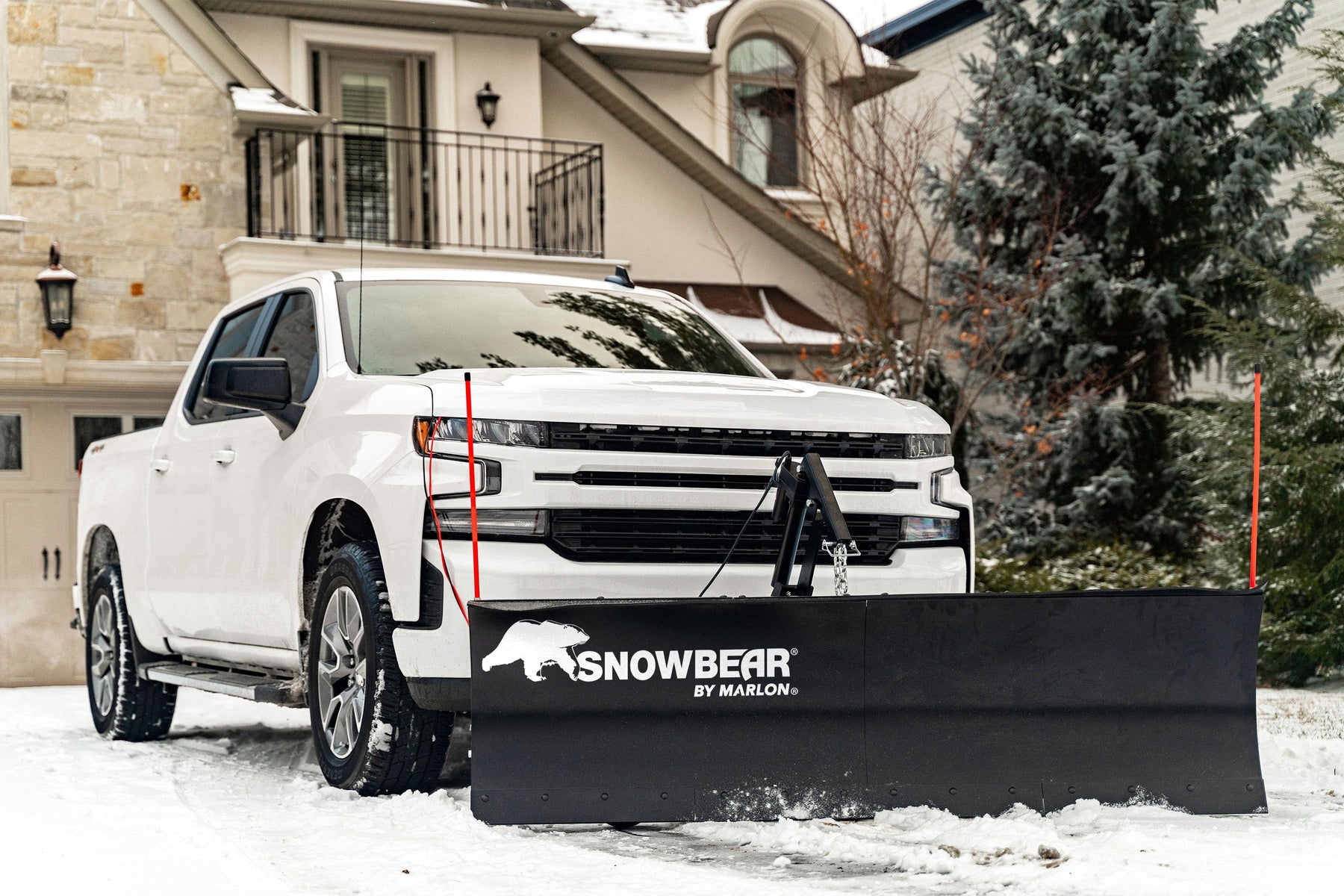 SnowBear by Marlon ELITE plow mounted on a white Chevrolet Silverado in a snowy driveway
