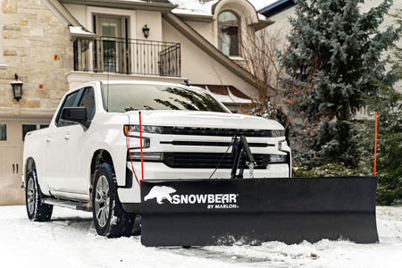 SnowBear by Marlon ELITE plow mounted on a white Chevrolet Silverado in a snowy driveway