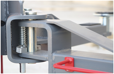 Close-up of the arm restraint pin and spring at the arm pivot with the red arm handle