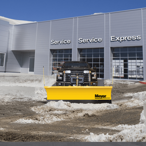 Pickup truck with a Meyer WingMan plow clearing slush in front of a service building
