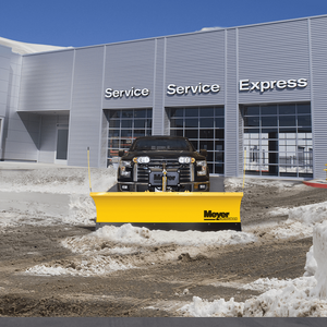 Pickup truck with a Meyer WingMan plow clearing slush in front of a service building