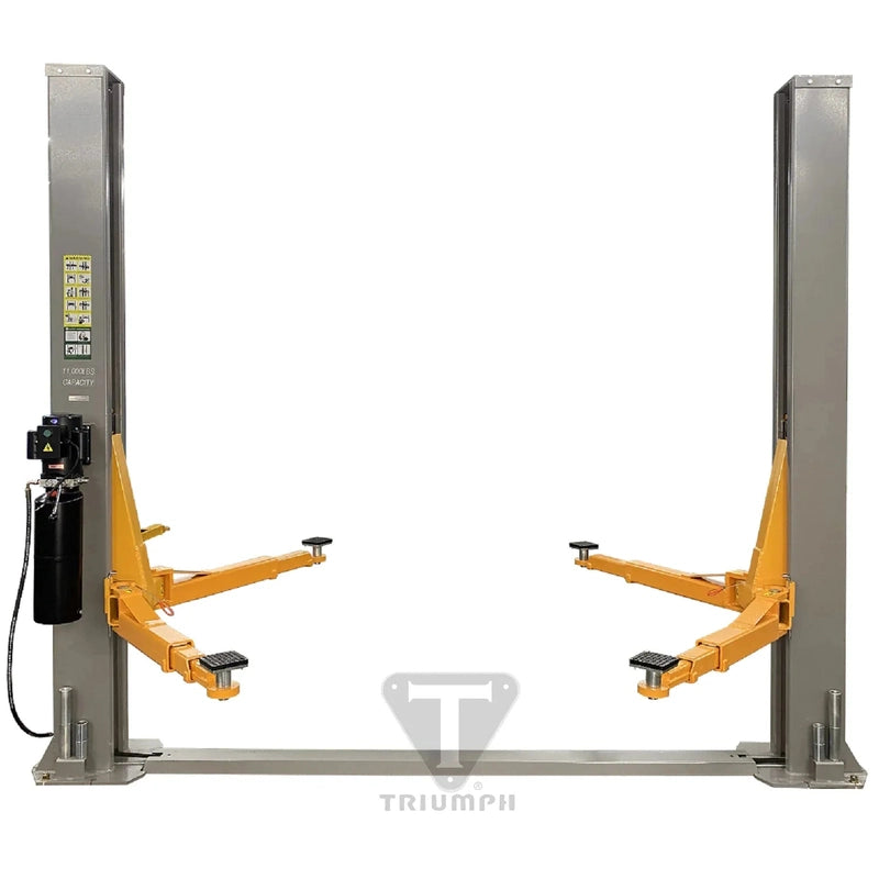 Triumph NT-11 two-post lift front view: grey columns on a floor base plate, orange swing arms, "11,000 LBS CAPACITY" marked on the column