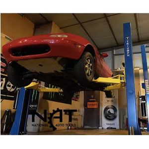 Red sports car raised on a Triumph two-post lift in a shop