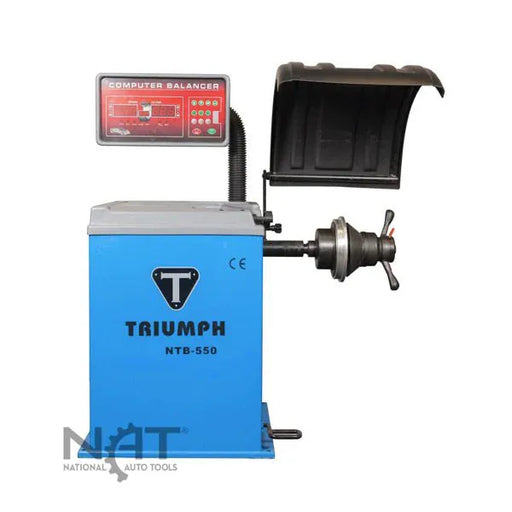 Triumph NTB-550 computer wheel balancer, blue cabinet with TRIUMPH branding, plastic safety hood, and computer display on flex arm