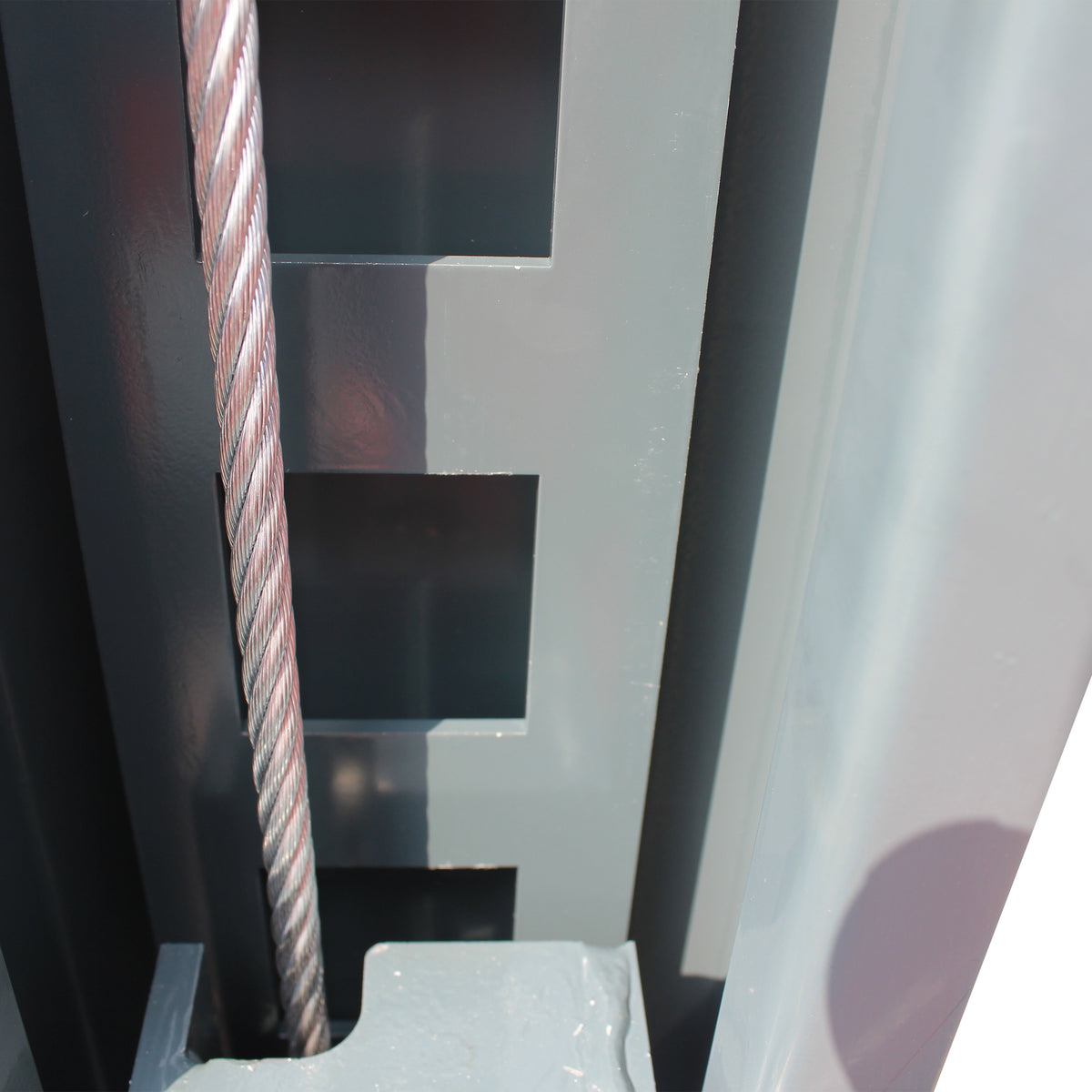 Steel lifting cable running past the slotted safety lock ladder inside a lift post