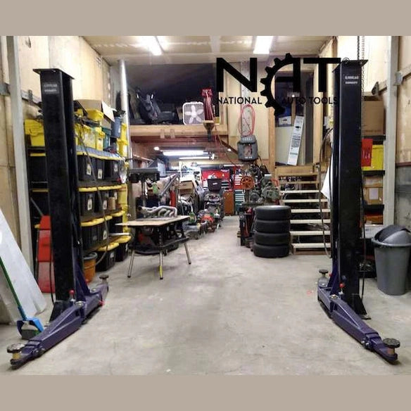 Two-post lift columns installed in a working garage with tools and tires