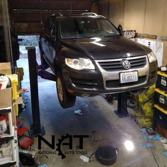 Dark Volkswagen SUV raised on the two-post lift inside a garage