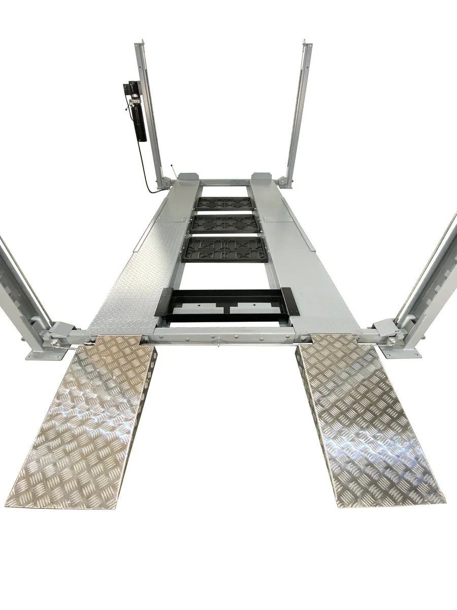 Drive-on view of Triumph NSS-8 X1 four-post lift with aluminum-look approach ramps and central drip trays
