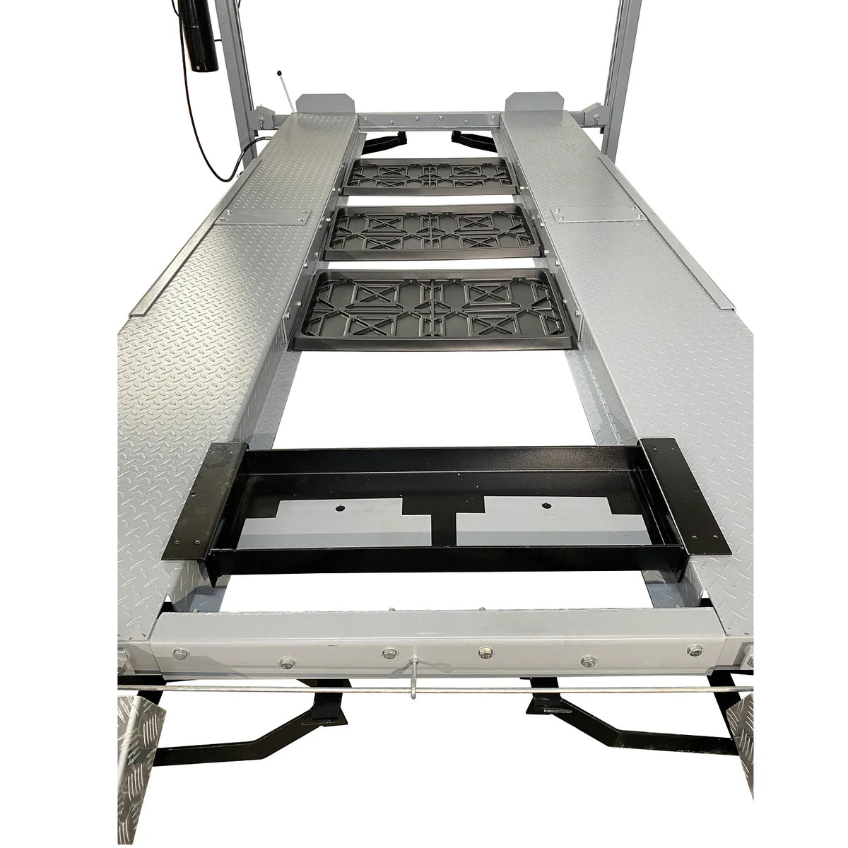 Three drip trays and jack tray installed between four-post lift runways, top-down view