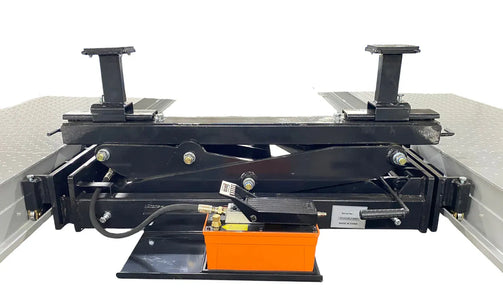 Triumph RJ-9000 rolling bridge jack at lowered position between four-post lift runways with orange foot-pump visible